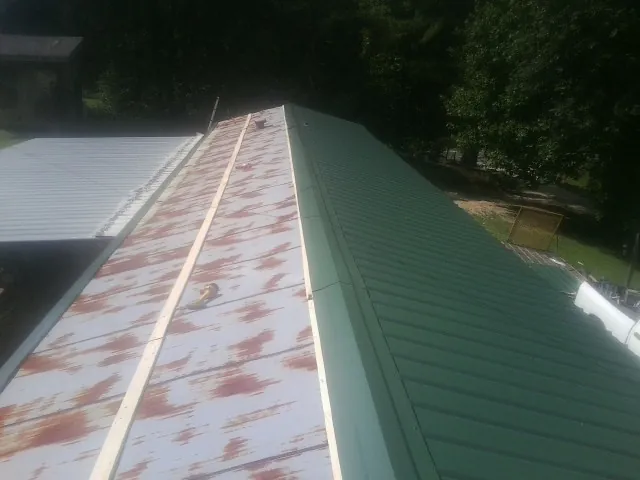 Old rusted panels beside newly installed green metal roofing — Wind Damage Roof Repair by Roofing Brothers in Reeseville