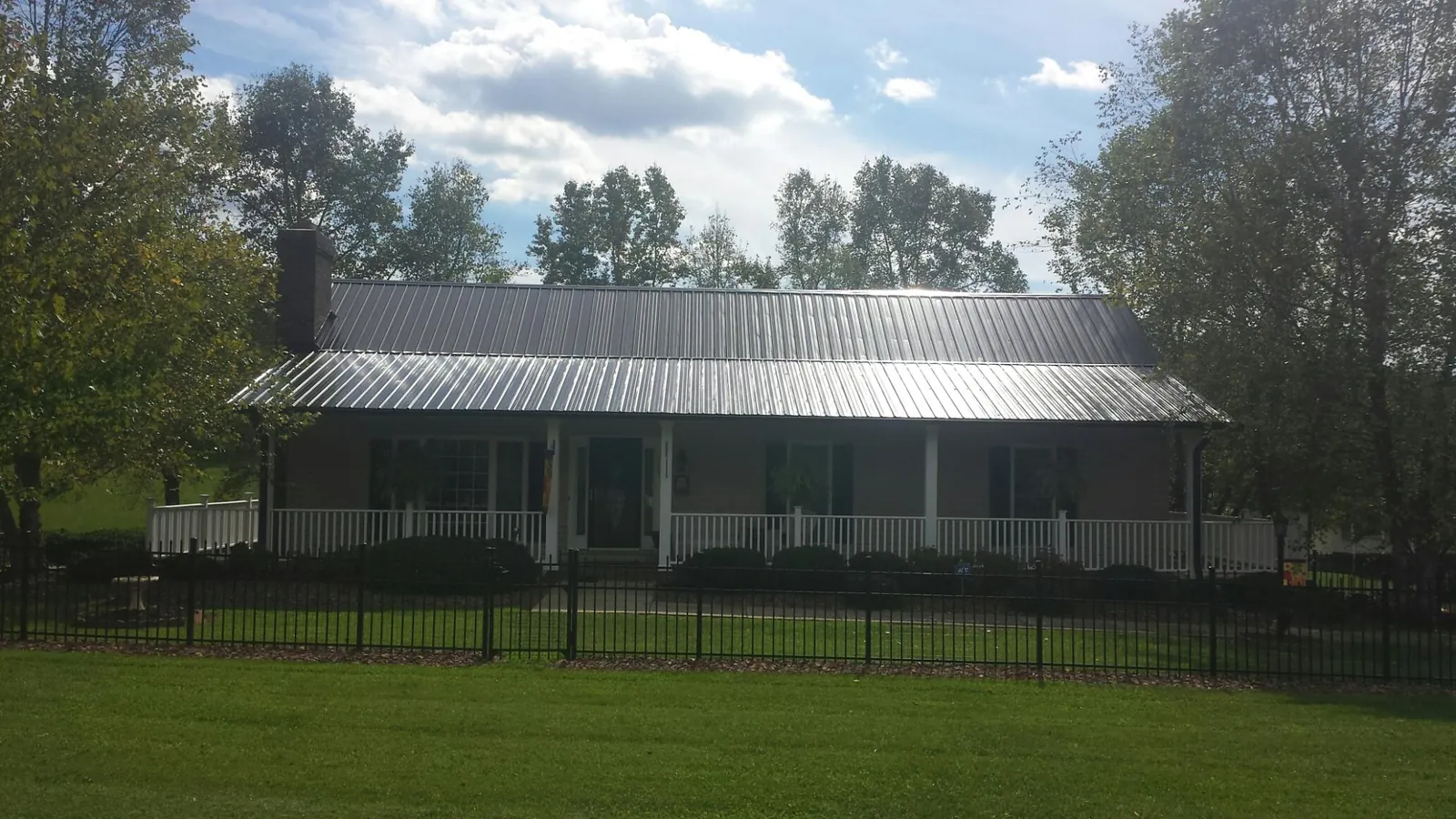 Gray metal roof on a brick ranch with a full width front porch — Gutter Guard Installation work by our crew in Reeseville